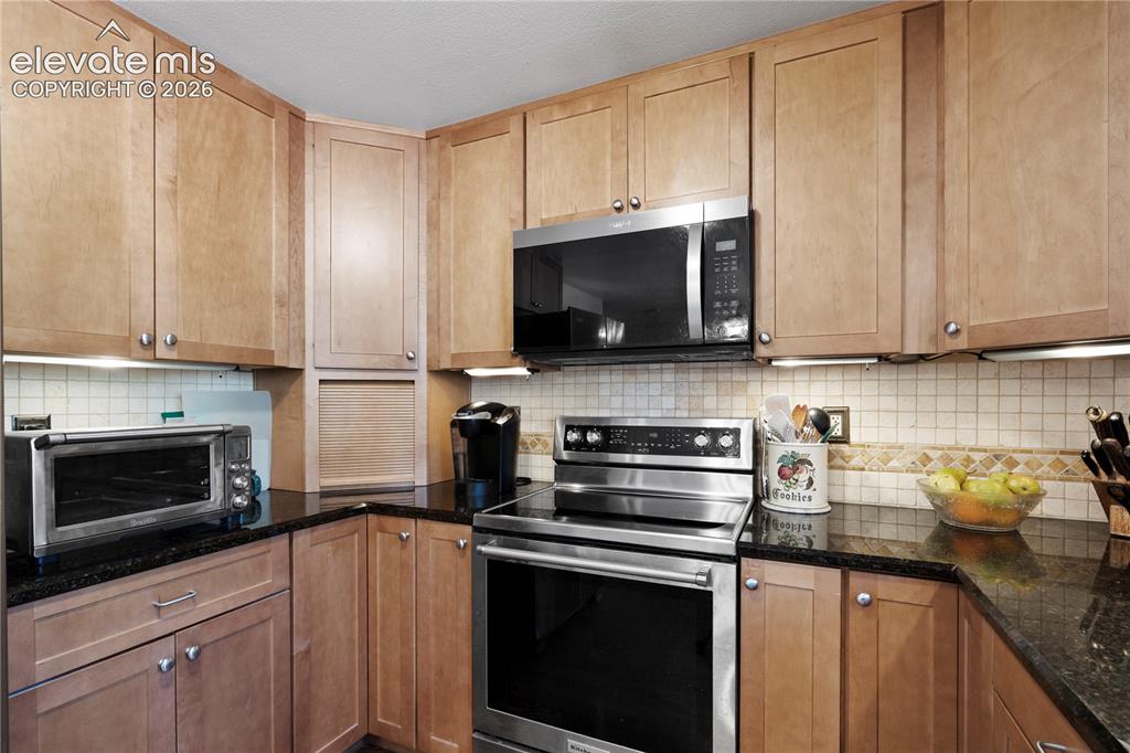 Image 11 of 43: Wood-finish cabinetry paired with dark countertops
