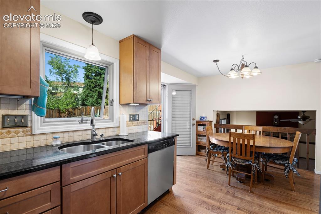 Image 12 of 43: Kitchen featuring wood-finish cabinetry, dark countertops, a double basin s
