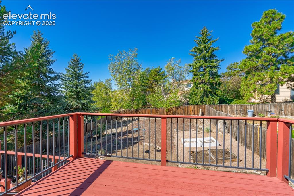 Image 17 of 43: Expansive deck with red wood flooring and black metal railings, overlooking
