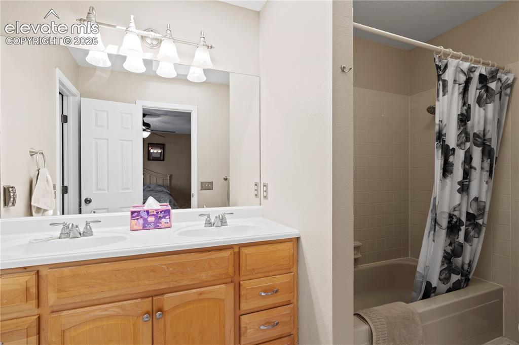 Image 18 of 43: Dual vanity with integrated sinks, wood-finish cabinetry, and a full-width