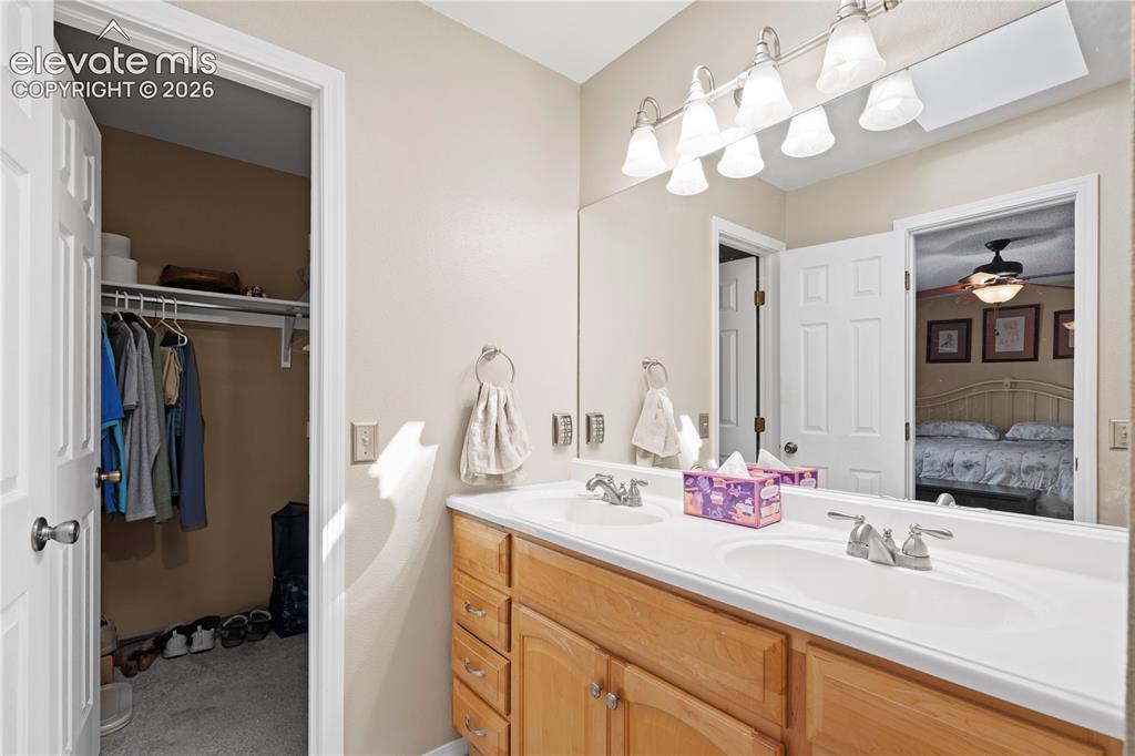 Image 19 of 43: Dual vanity with integrated sinks, wood-finish cabinetry, and brushed nicke
