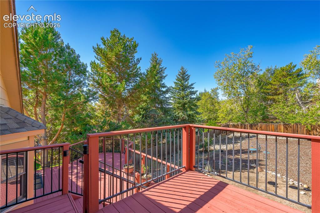 Image 25 of 43: Expansive multi-level deck with red-stained wood and black metal railings,