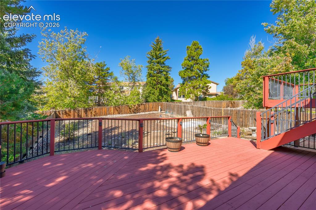 Image 26 of 43: Expansive outdoor deck with red-stained wood flooring and black metal raili