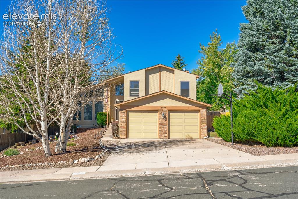Image 3 of 43: Two-story residence with a two-car garage, stone-clad facade details, and a