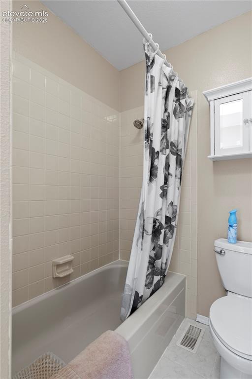 Image 42 of 43: Recessed bathtub with surrounding tile, showerhead, and a wall-mounted stor