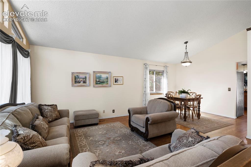 Image 7 of 43: Vaulted ceiling with a decorative chandelier, wood-finish flooring, and amp