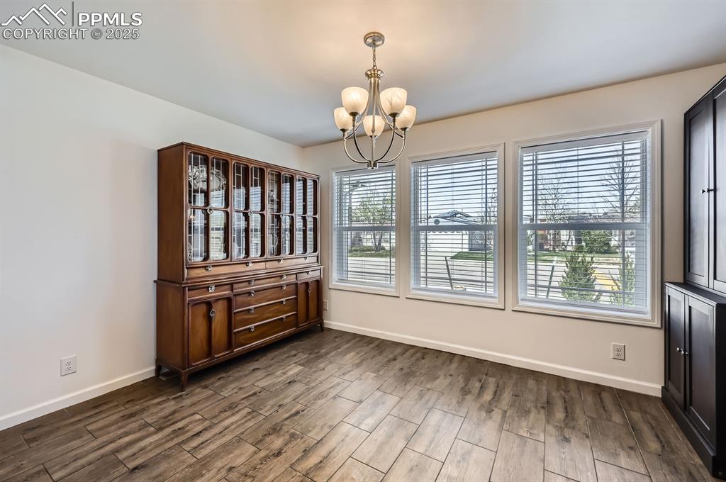 Image 13 of 28: Unfurnished dining area featuring a chandelier and dark wood finished floor
