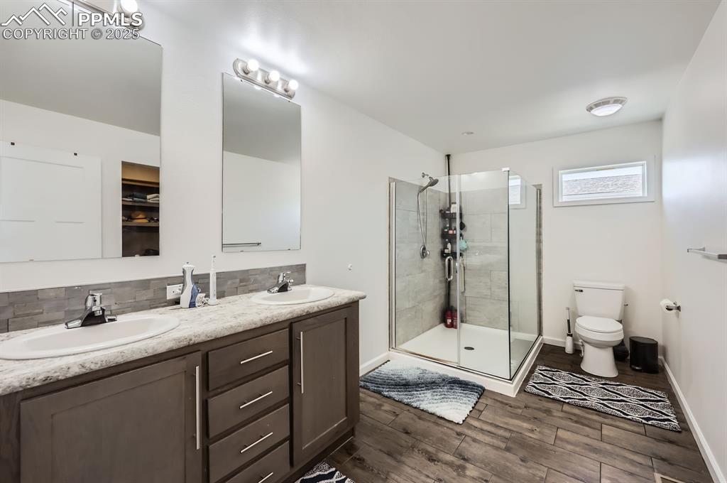 Image 17 of 28: Full bath with wood finished floors, double vanity, a shower stall, and dec