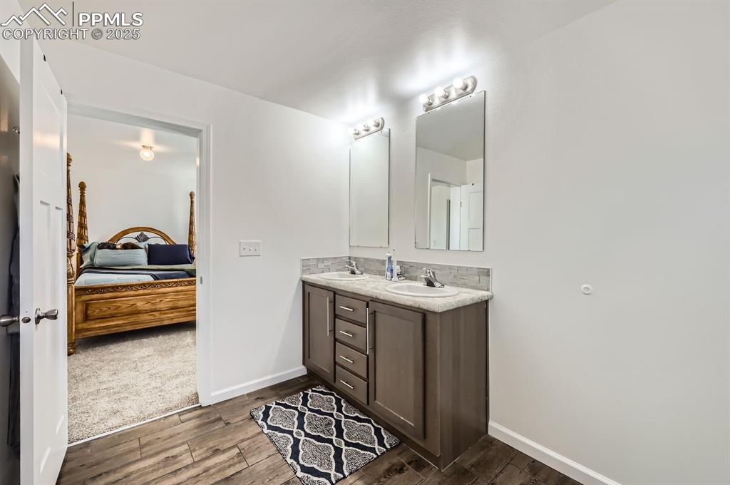 Image 18 of 28: Ensuite bathroom featuring double vanity and wood finished floors