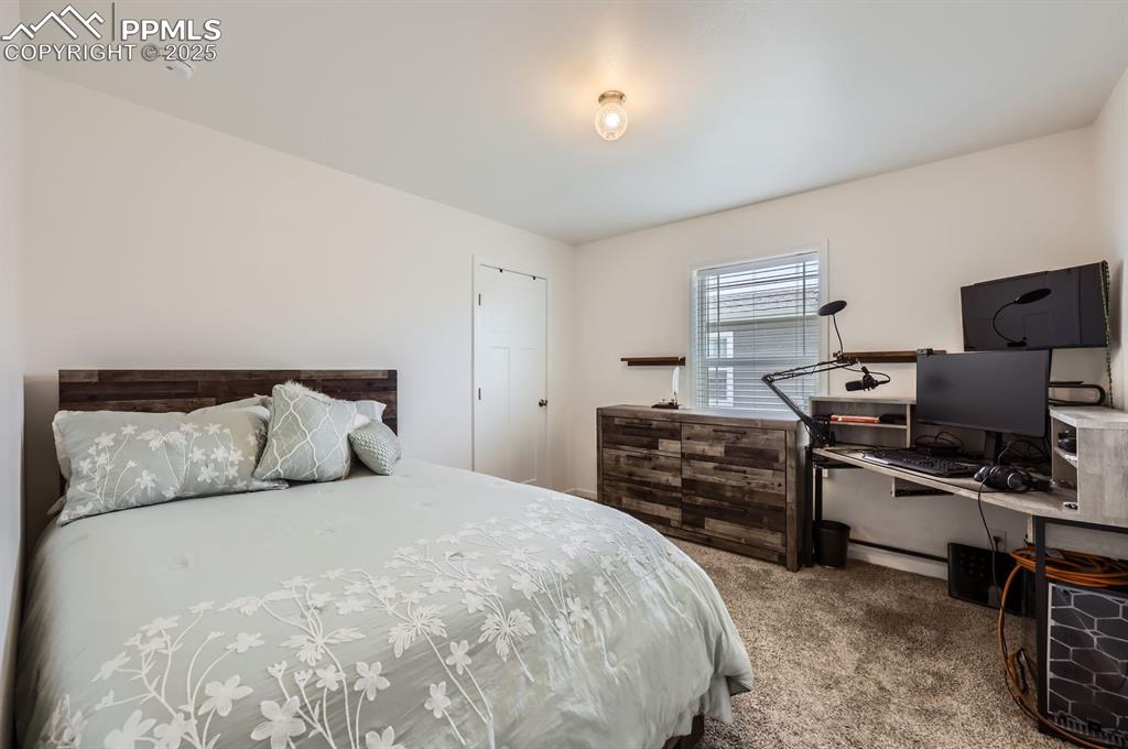 Image 19 of 28: Bedroom with carpet floors and a desk