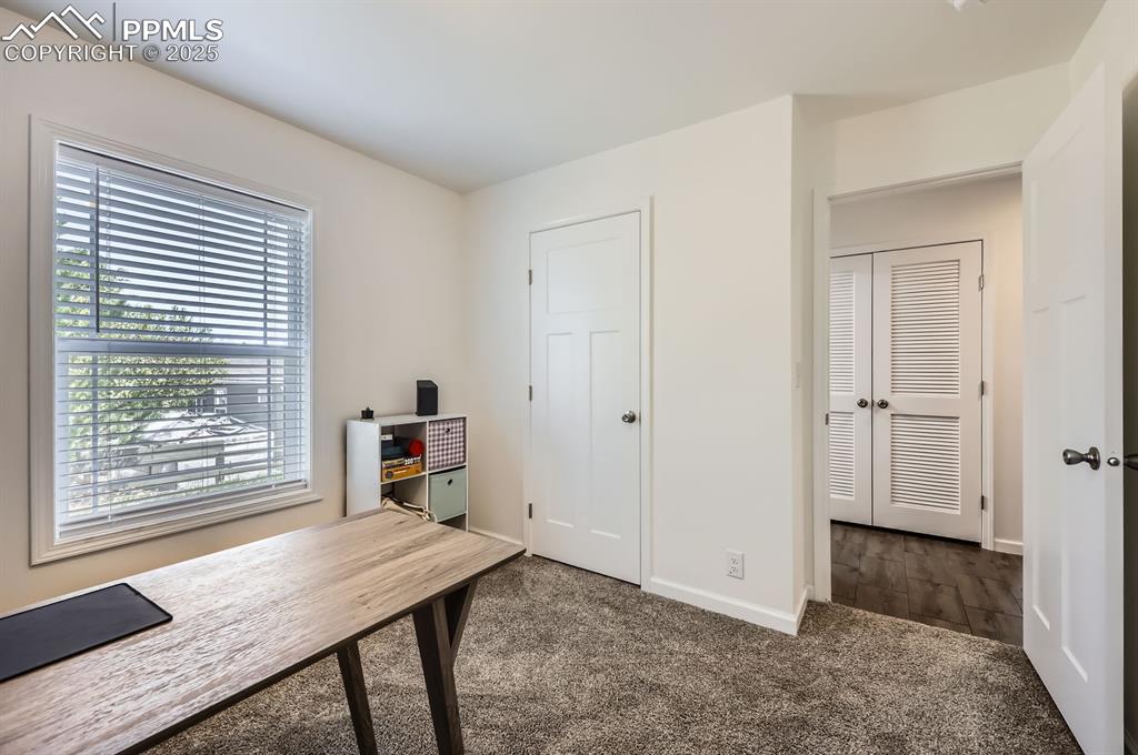 Image 24 of 28: Home office featuring dark carpet and baseboards