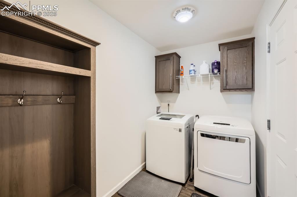 Image 26 of 28: Laundry room featuring separate washer and dryer, cabinet space, and wood f