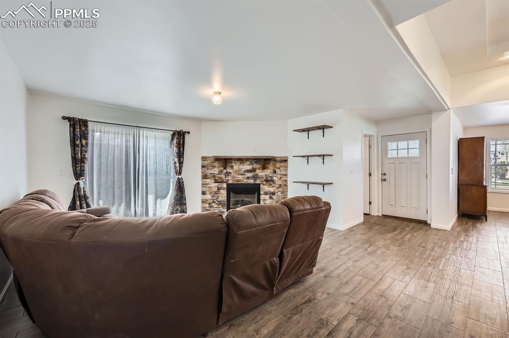 Image 6 of 28: Living room with wood finished floors and a stone fireplace
