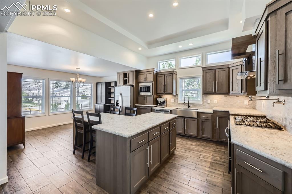 Image 8 of 28: Kitchen with decorative backsplash, recessed lighting, a center island, a c