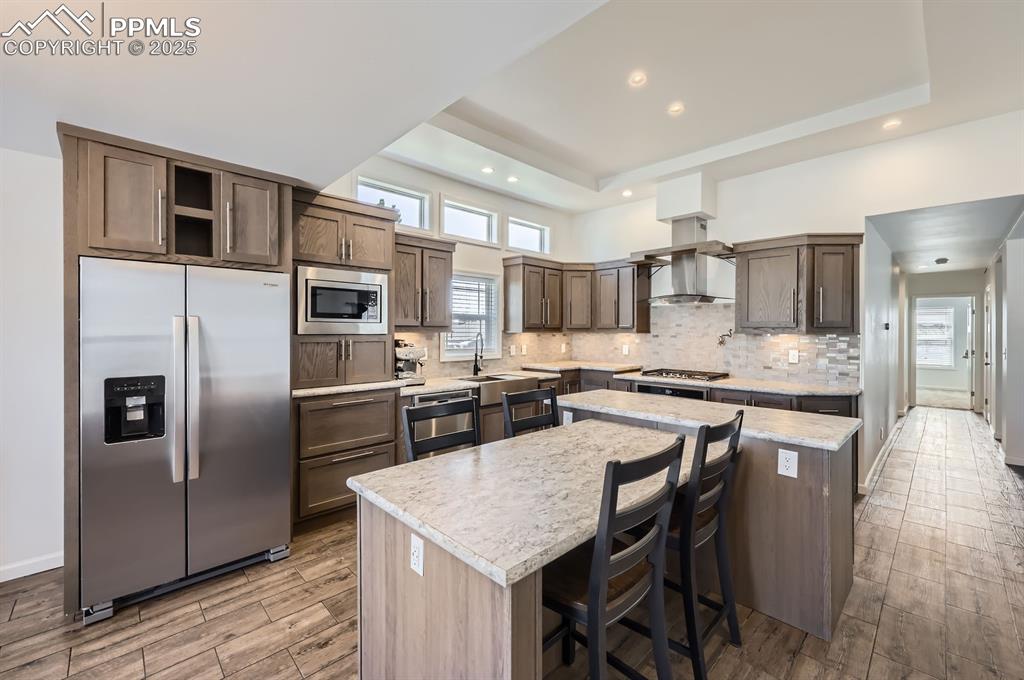 Image 9 of 28: Kitchen with stainless steel appliances, light wood-style flooring, a cente