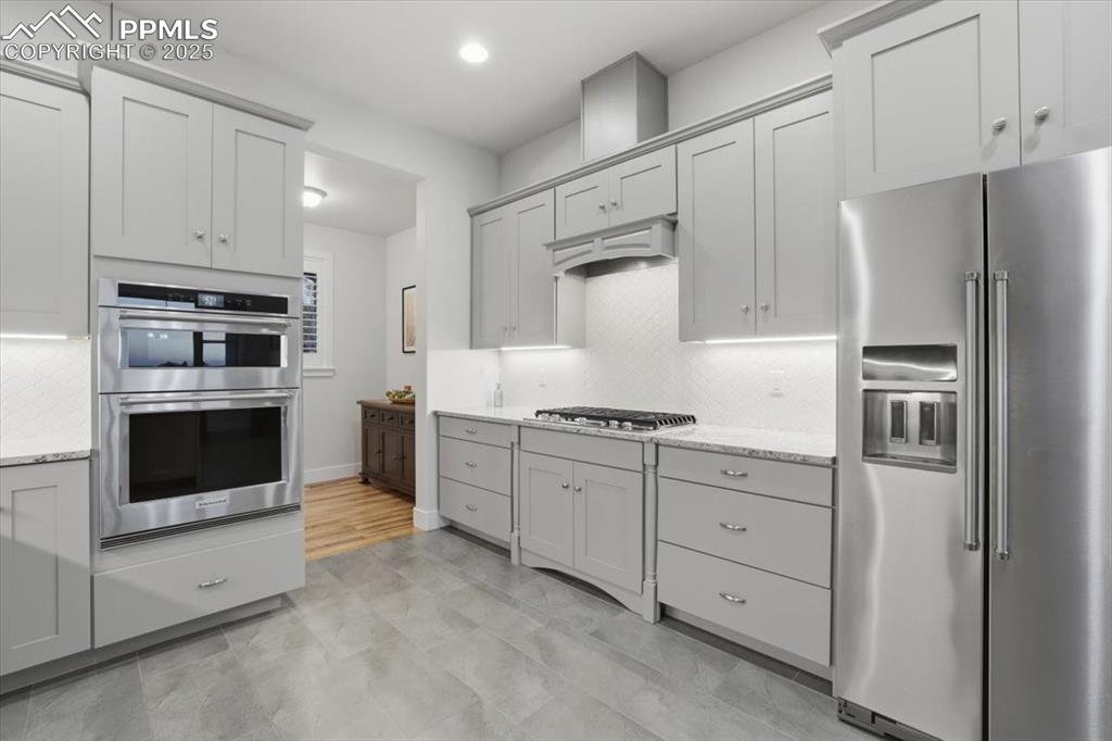 Image 16 of 49: The upscale appliances include a gas cooktop with recessed vent hood, conve