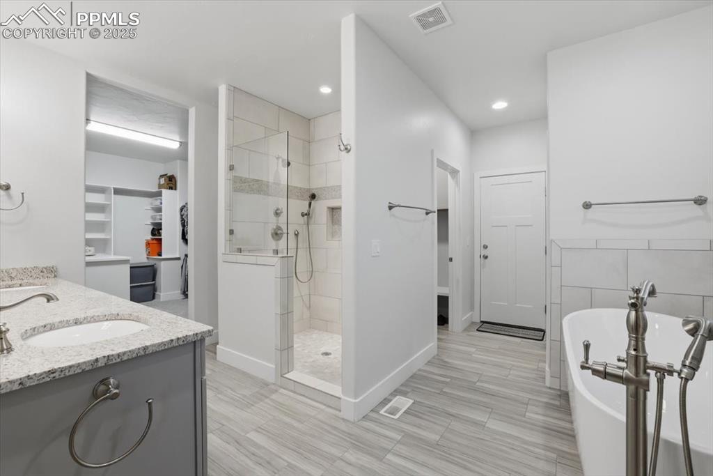 Image 22 of 49: The primary bathroom features dual vanities, a separate tub and shower and