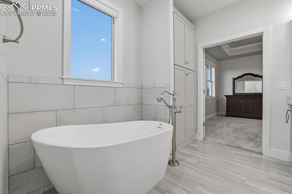 Image 24 of 49: The primary bathroom has an elegant soaking tub with floor-mounted fixtures