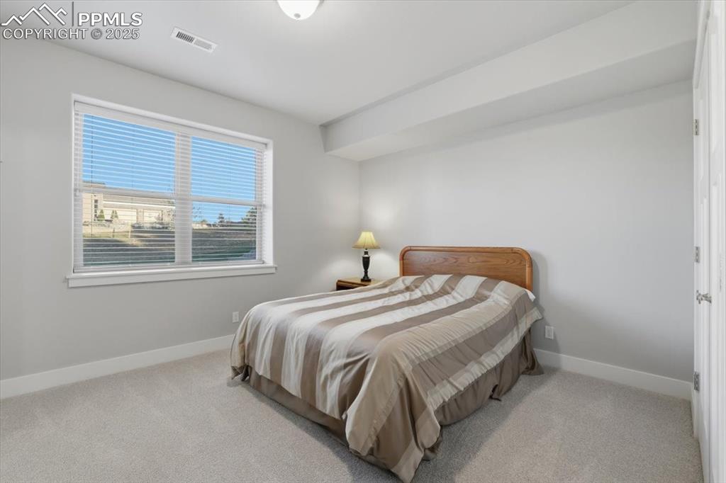 Image 44 of 49: The fifth bedroom is located on the basement level, with a garden-level win