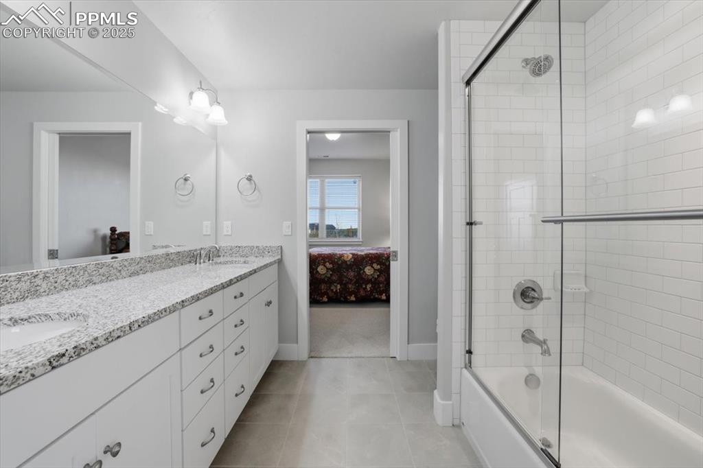 Image 45 of 49: This spacious basement-level bathroom features a tub/shower combo and dual