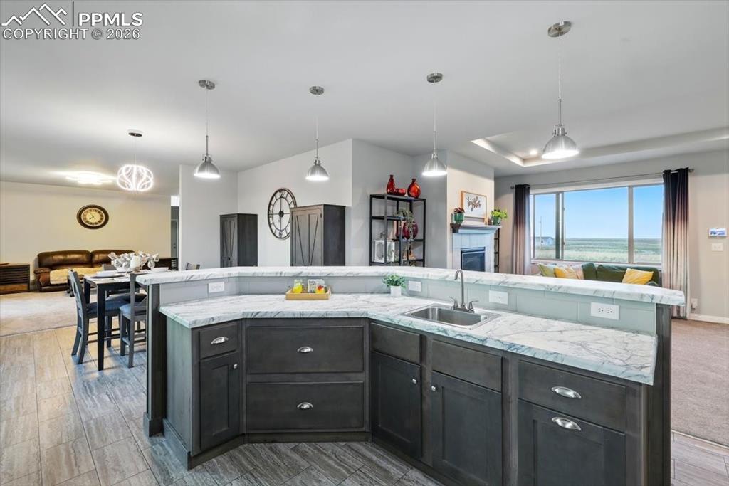 Image 11 of 30: Kitchen featuring a sink, open floor plan, light stone counters, and a cent