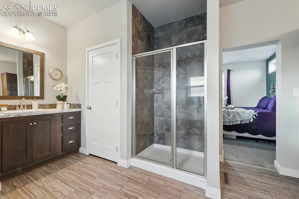 Image 18 of 30: Bathroom featuring ensuite bathroom, vanity, a shower stall, and wood finis