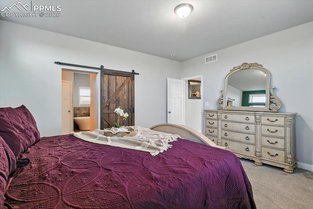 Image 19 of 30: Carpeted bedroom with a barn door