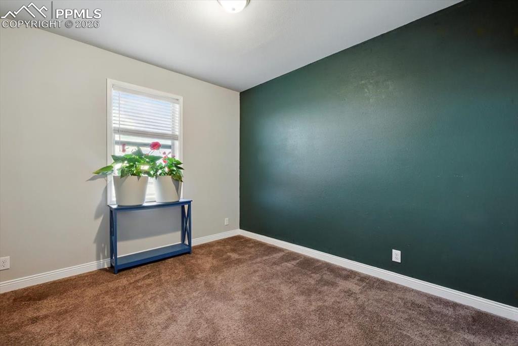 Image 22 of 30: Empty room featuring dark carpet and baseboards