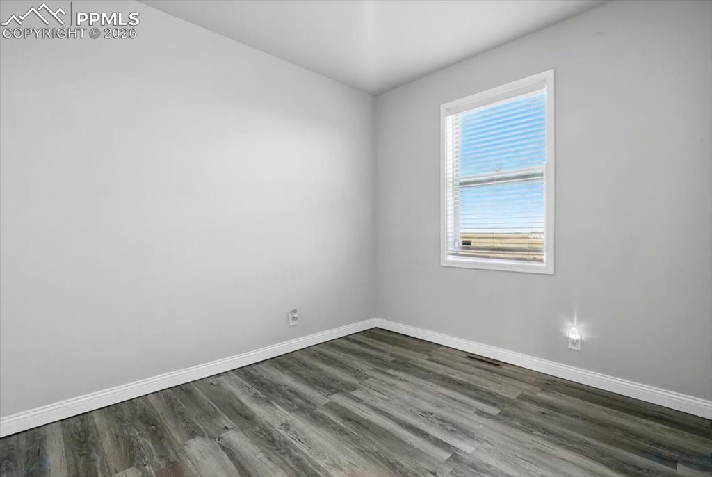Image 24 of 30: Spare room with baseboards and dark wood-type flooring