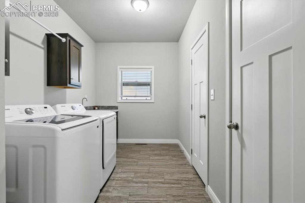 Image 27 of 30: Washroom featuring cabinet space, independent washer and dryer, baseboards,