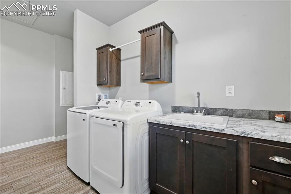 Image 28 of 30: Laundry room with washer and dryer, cabinet space, light wood finished floo