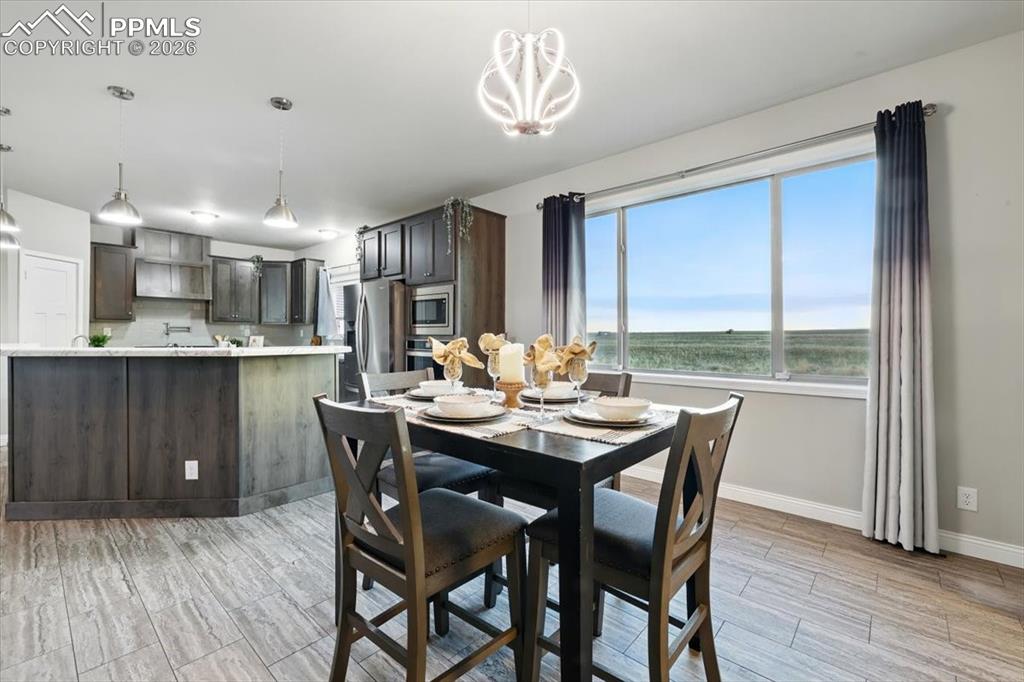 Image 9 of 30: Dining area with baseboards, a chandelier, wood tiled floors, and a water v