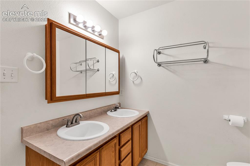 Image 17 of 32: Double vanity with wood-finish cabinetry and integrated sinks, complemented