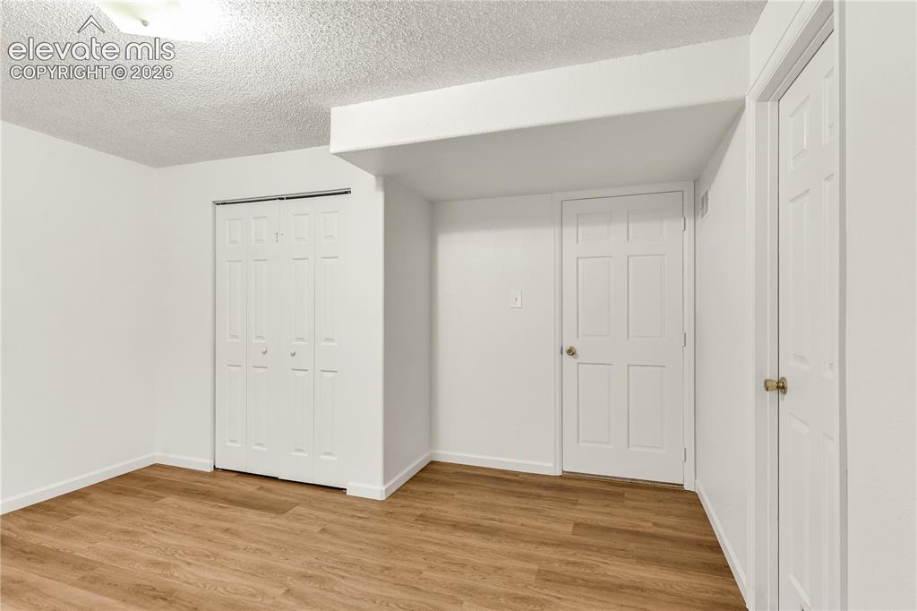 Image 23 of 32: Room featuring wood-finish flooring, white painted walls, a flush-mount cei