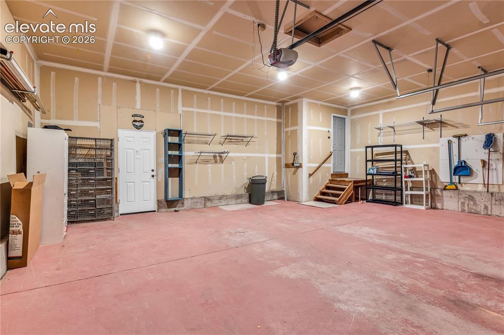 Image 27 of 32: Spacious garage featuring a finished ceiling, multiple light fixtures, and