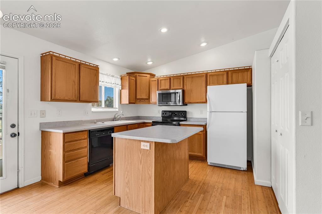 Image 9 of 32: Kitchen featuring wood-finish flooring, wood cabinetry, a center island, an