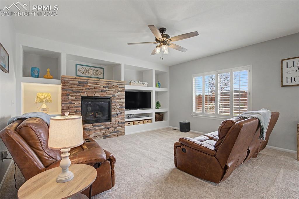 Image 12 of 49: Living area featuring a stone-faced fireplace with a built-in media center,