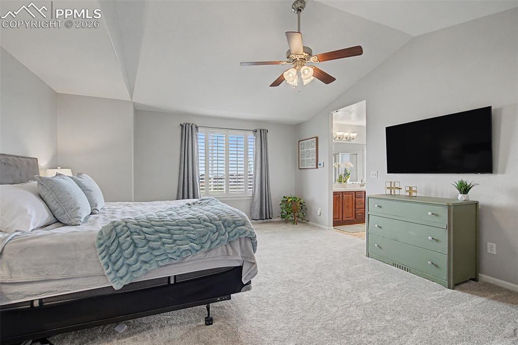 Image 20 of 49: Spacious room featuring vaulted ceilings, a ceiling fan with light fixture,