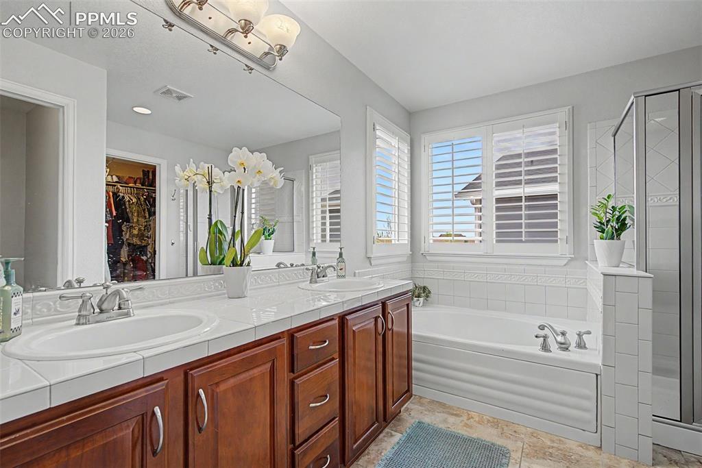 Image 24 of 49: Bathroom featuring a dual vanity with wood cabinetry, tiled countertops, an