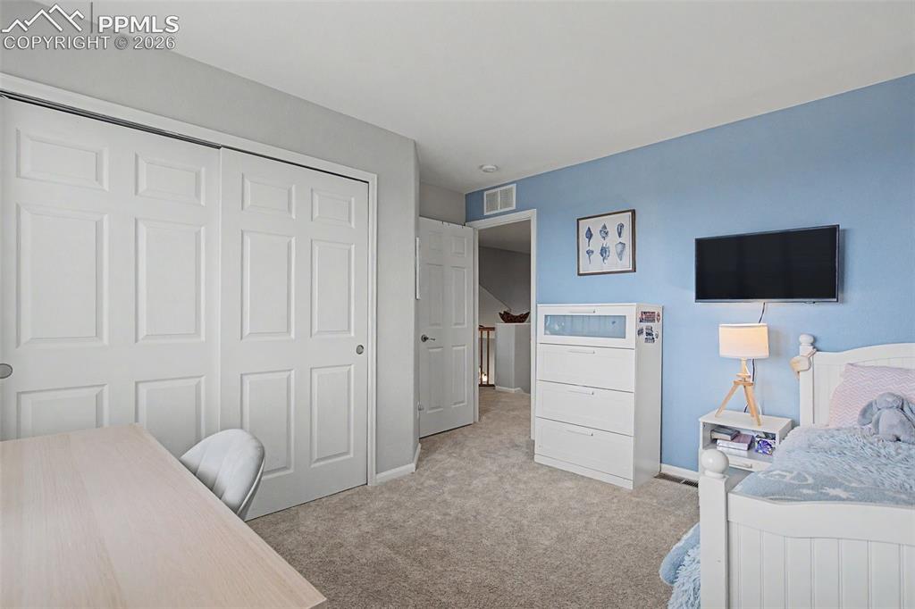 Image 28 of 49: Carpeted room featuring a double bi-fold closet with paneled doors and a li