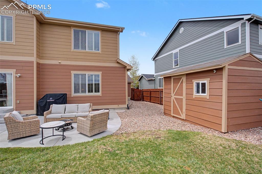 Image 39 of 49: Curved concrete patio with an adjacent storage shed featuring a small windo