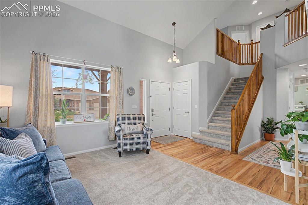 Image 5 of 49: Vaulted ceiling living area featuring a large window, light gray carpeting,