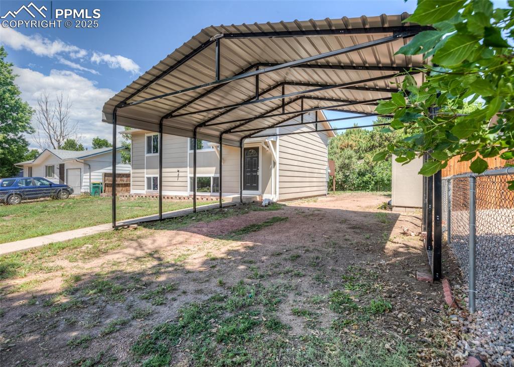 Image 47 of 48: View of parking with a detached carport and exterior storage sheds
