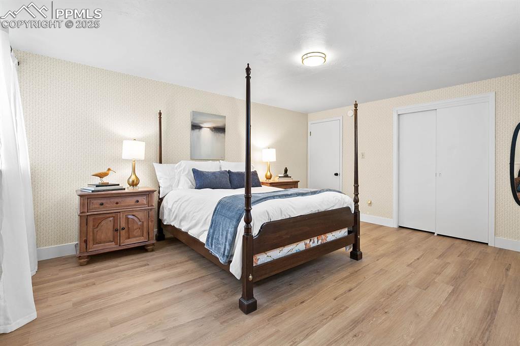 Image 11 of 45: Bedroom with wallpapered walls, light wood-style flooring, and a closet