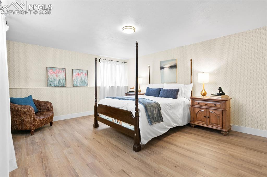 Image 13 of 45: Bedroom with wallpapered walls and light wood-style floors