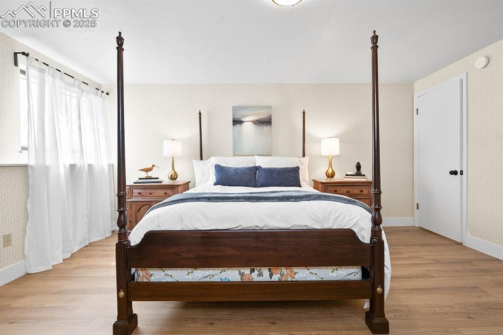 Image 14 of 45: Bedroom with wallpapered walls and light wood-style floors