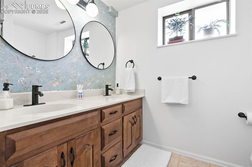 Image 16 of 45: Bathroom with double vanity, tile patterned flooring, and wallpapered walls