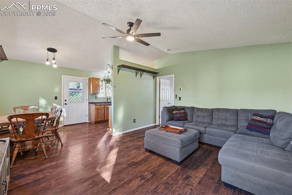 Image 10 of 23: Living area with dark wood-style floors, ceiling fan, and a textured ceilin