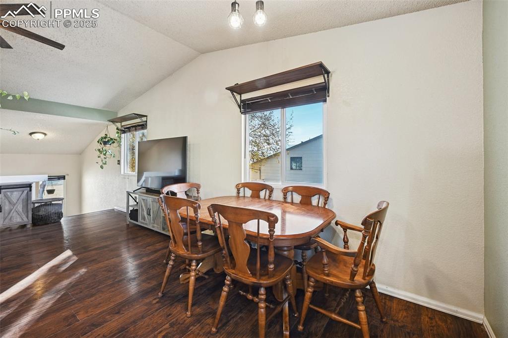 Image 12 of 23: Dining room featuring a textured ceiling, dark wood finished floors, vaulte