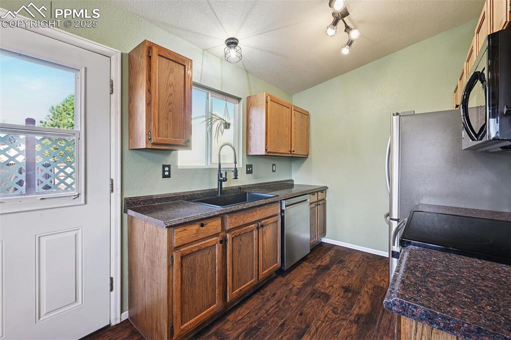 Image 14 of 23: Kitchen with dark countertops, black appliances, dark wood-style floors, br